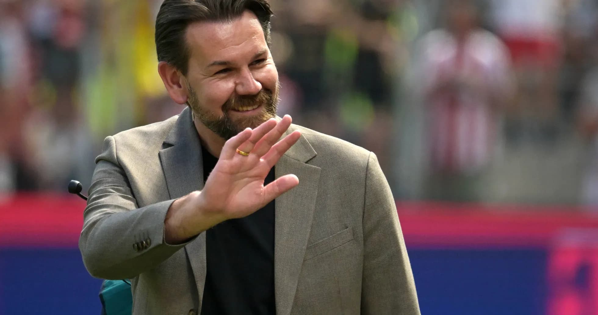 Man in suit waving during a sporting event