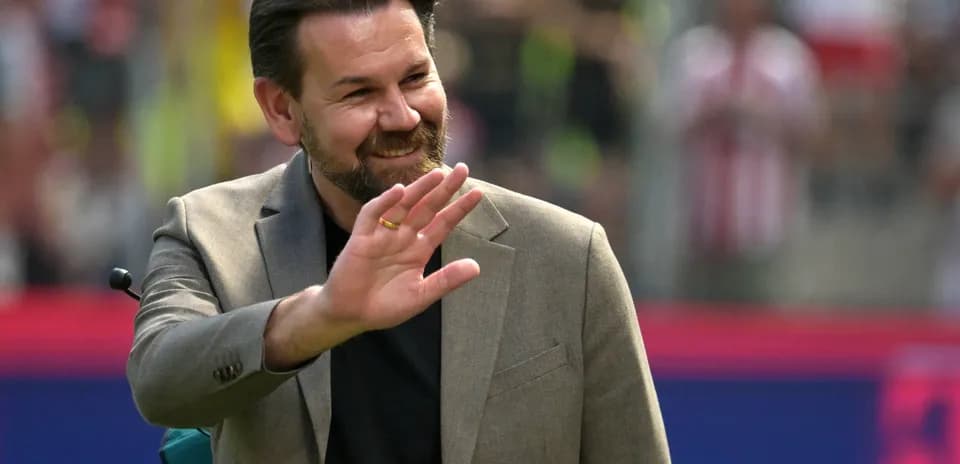 Man in suit waving during a sporting event