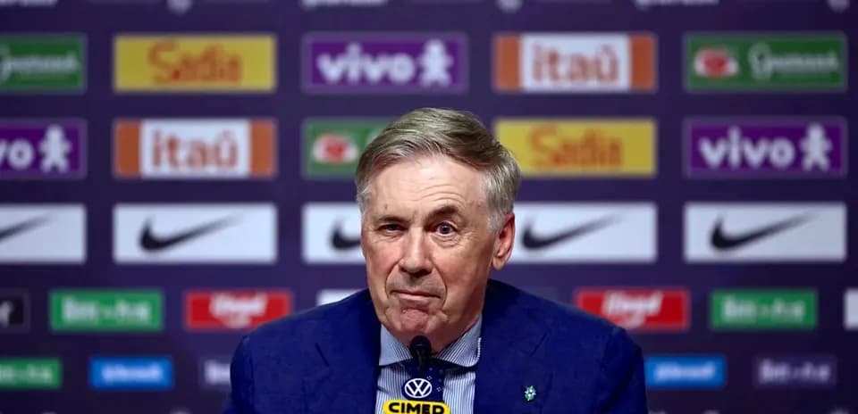 Coach speaking at press conference with logos in background
