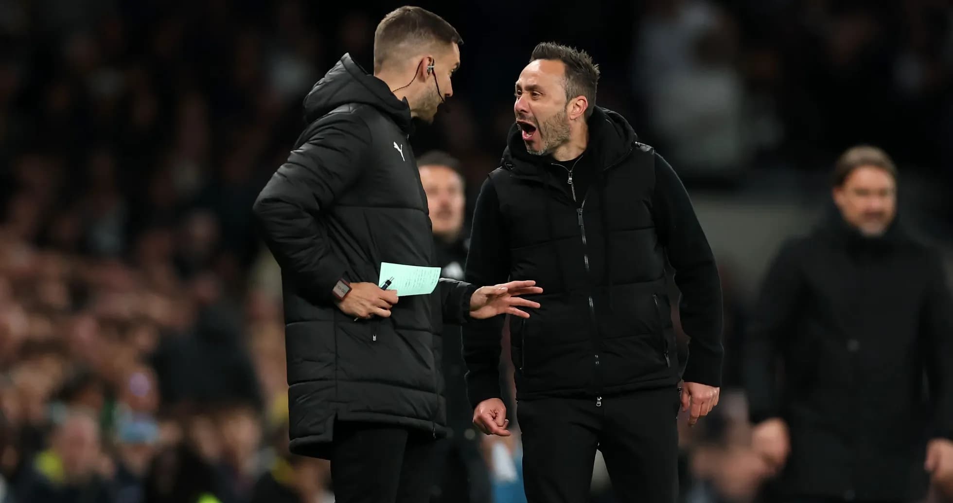 Two coaches discussing animatedly on the sidelines