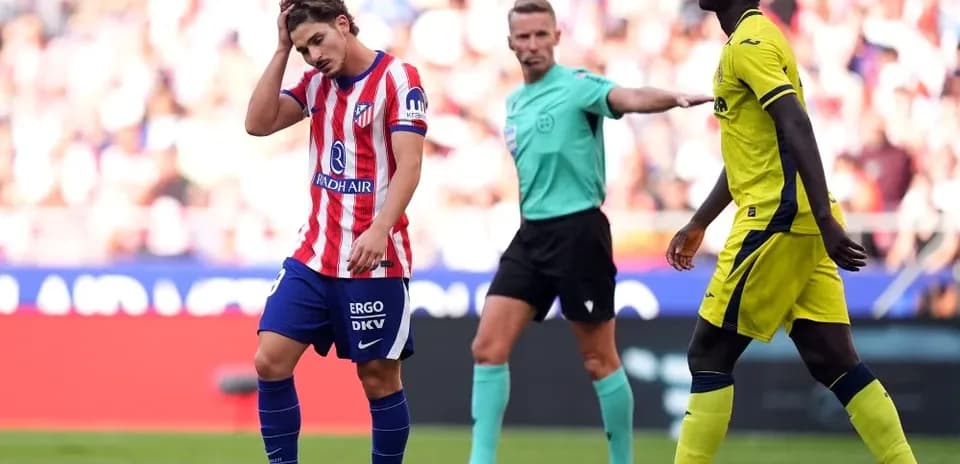 Atletico player reacting during match with referee nearby