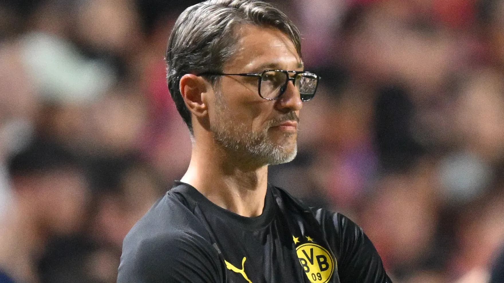 Coach observing match with arms crossed