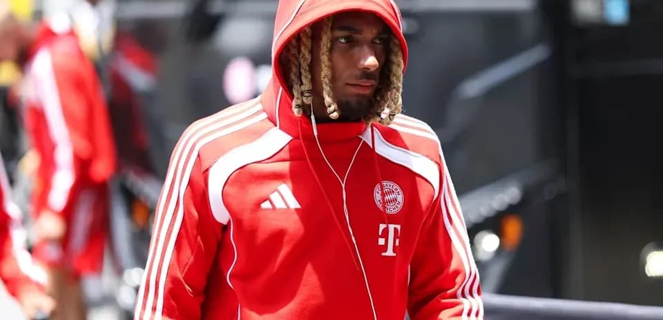 Player in red hoodie arriving at team bus