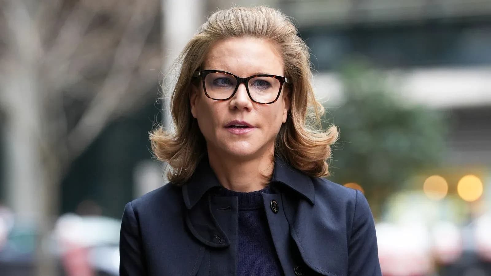 Woman with glasses walking outdoors in urban setting