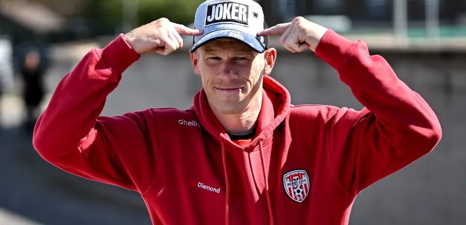 Man wearing 'JOKER' cap and red hoodie