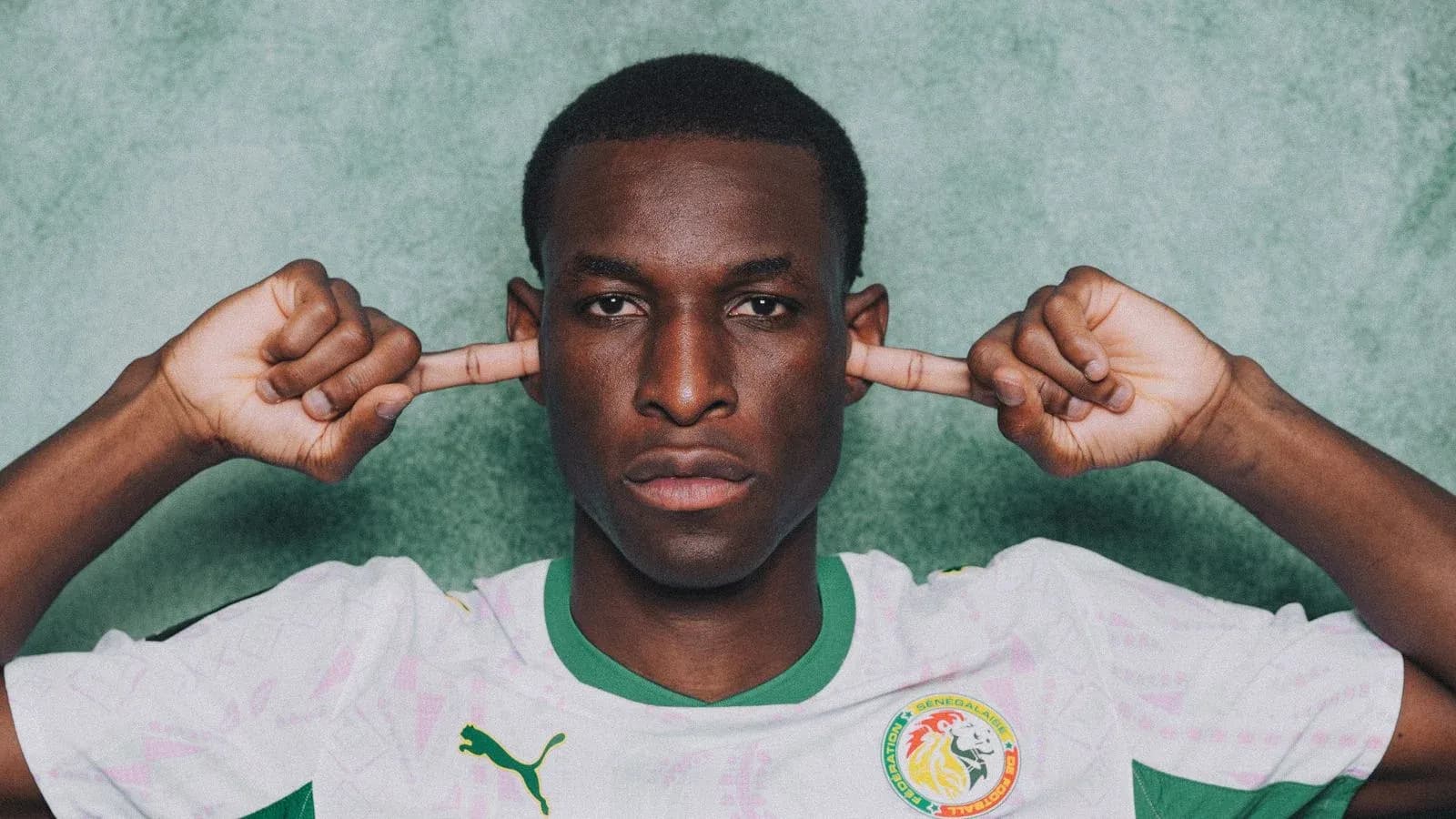 Football player in Senegal jersey covering ears
