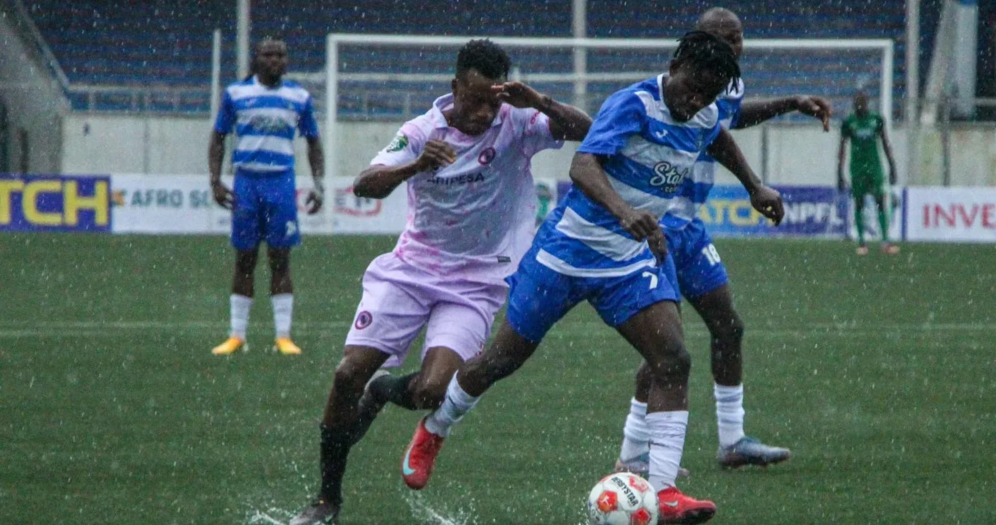 Players battling for the ball in rainy match