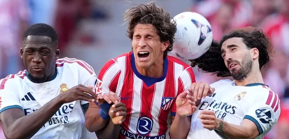 Players from Atletico and Real Madrid contesting a header