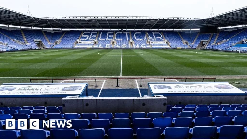 Empty football stadium with blue seating and pitch
