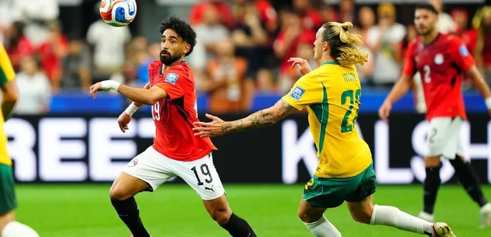 Egyptian player dribbling past Australian defender during match