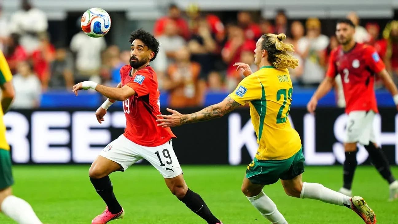 Egyptian player dribbling past Australian defender during match