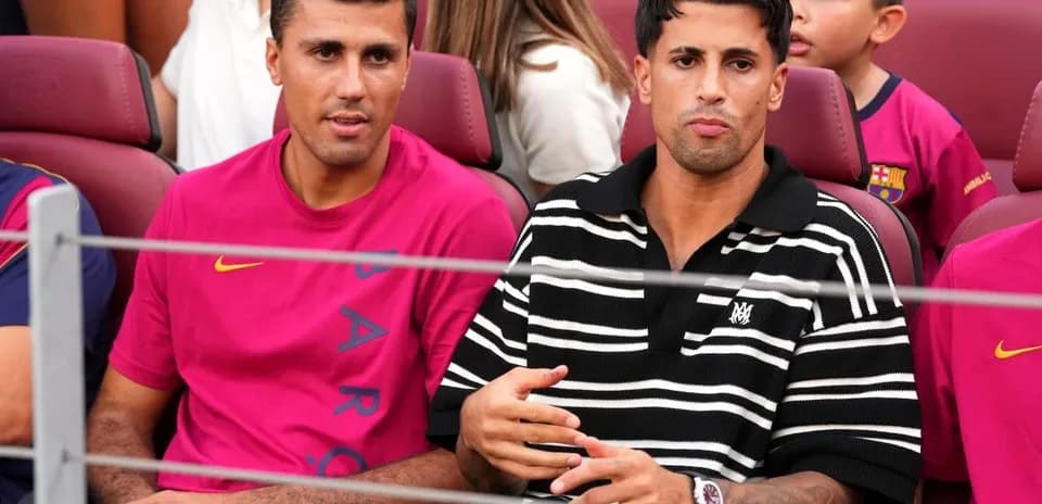 Two men sitting in stadium seats, wearing team colors