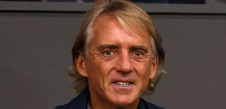 Man smiling while seated in a stadium box