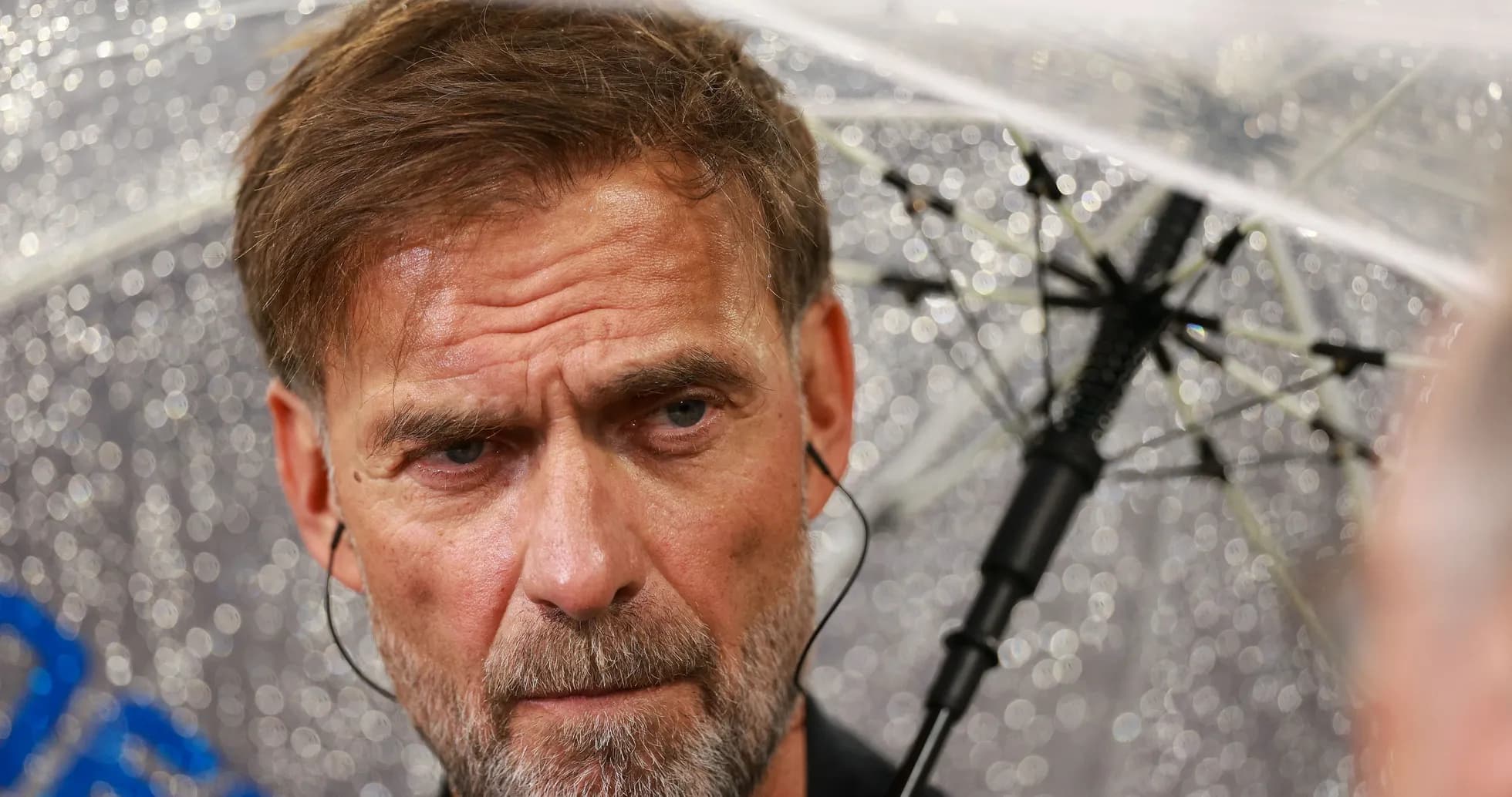 Coach under umbrella during rainy press conference