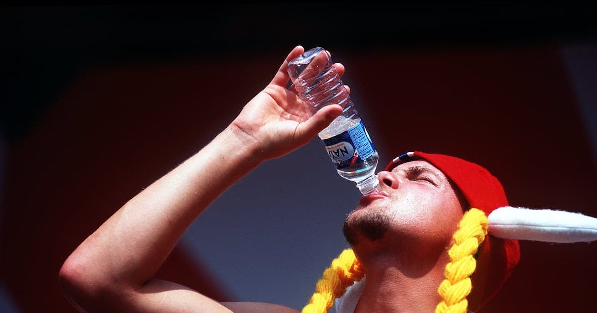 Person drinking water from a bottle, wearing a hat