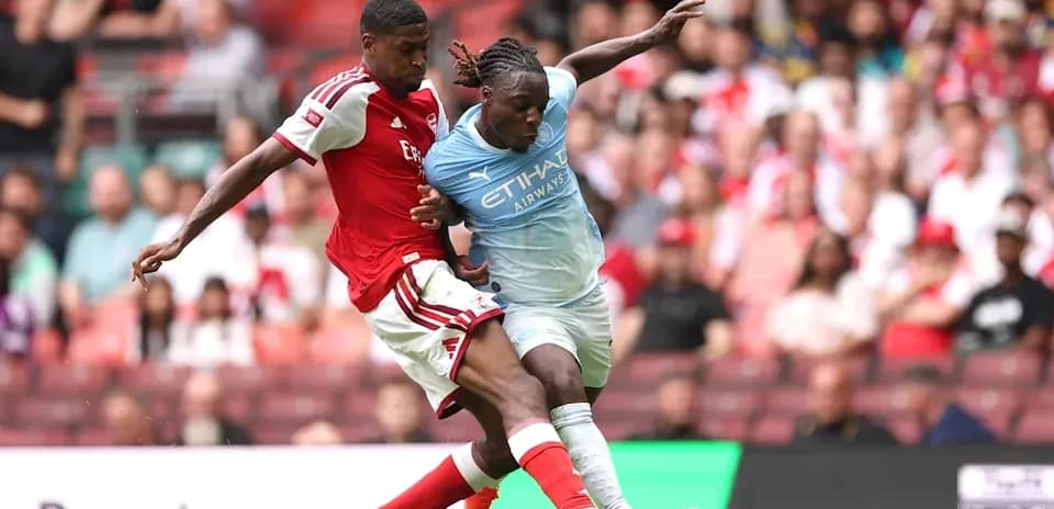 Arsenal player tackling Manchester City player during match