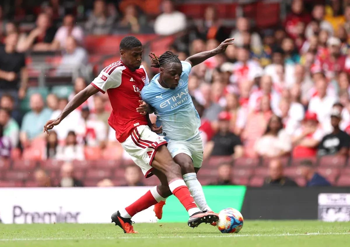 Arsenal player tackling Manchester City player during match