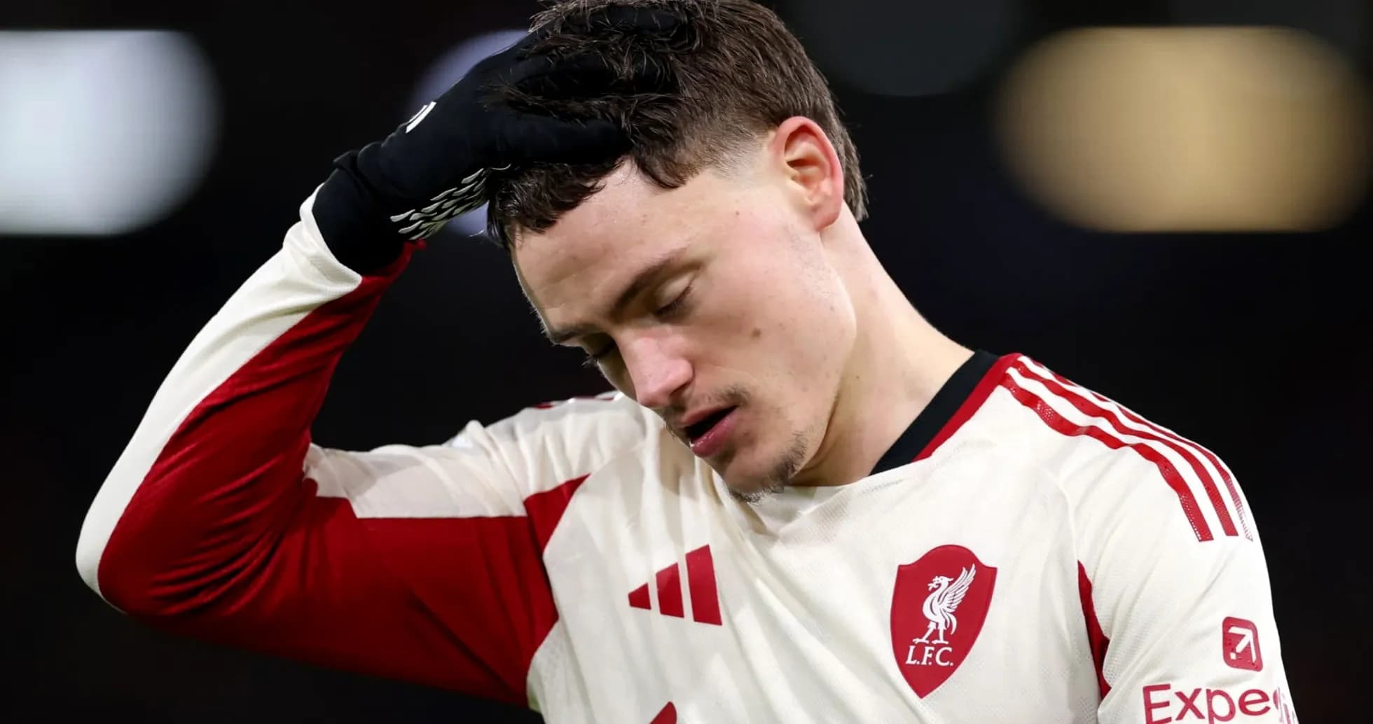 Player in Liverpool jersey looking down with concern