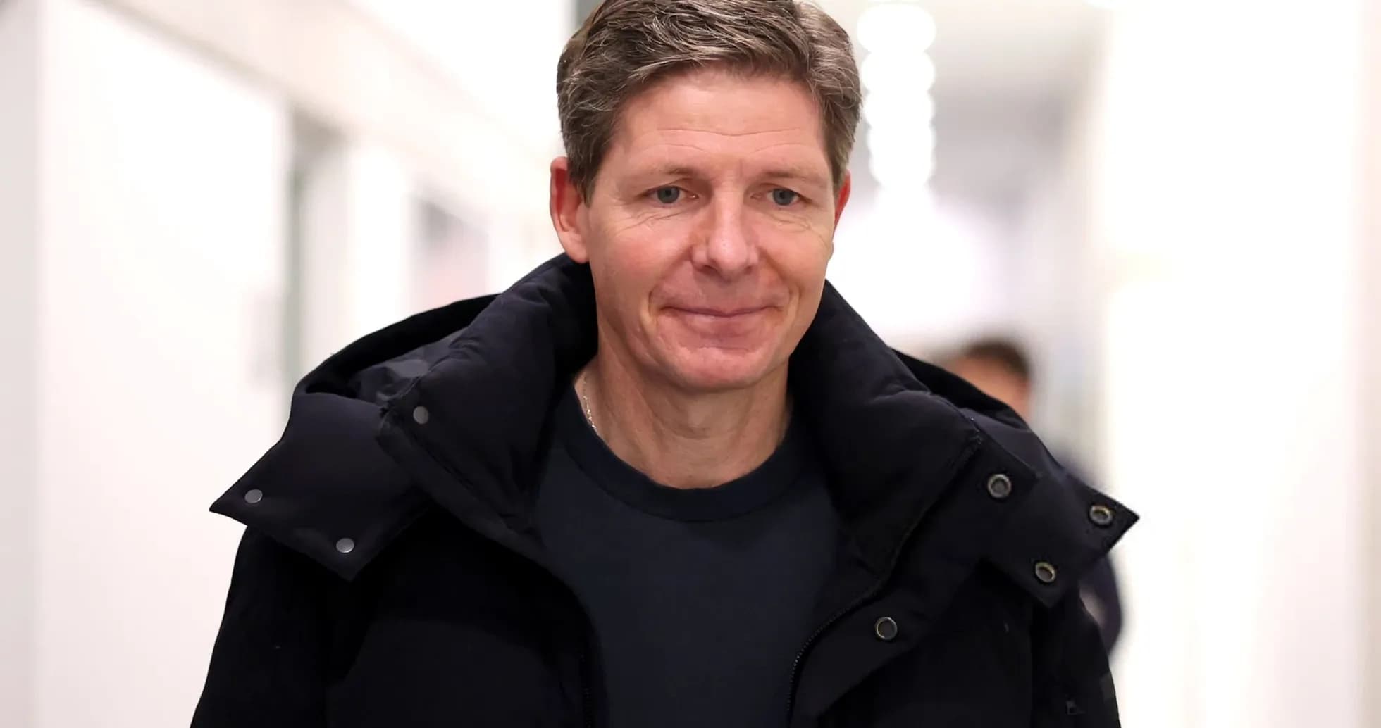 Person walking in a corridor wearing a black coat
