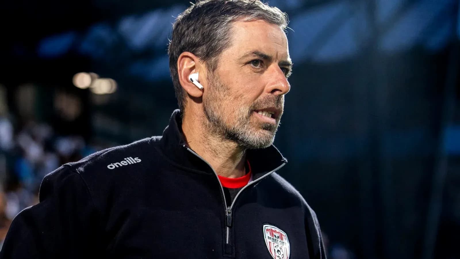 Coach with earbuds observing the match