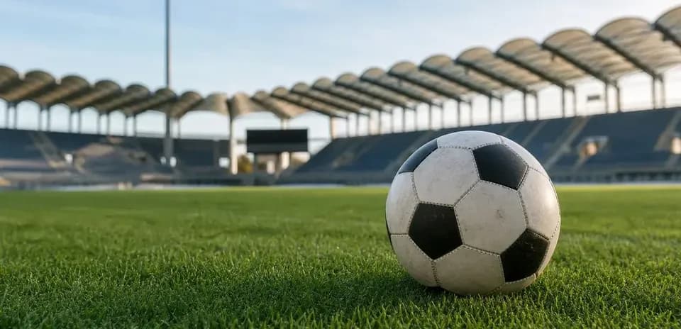 Soccer ball on grass pitch at empty stadium