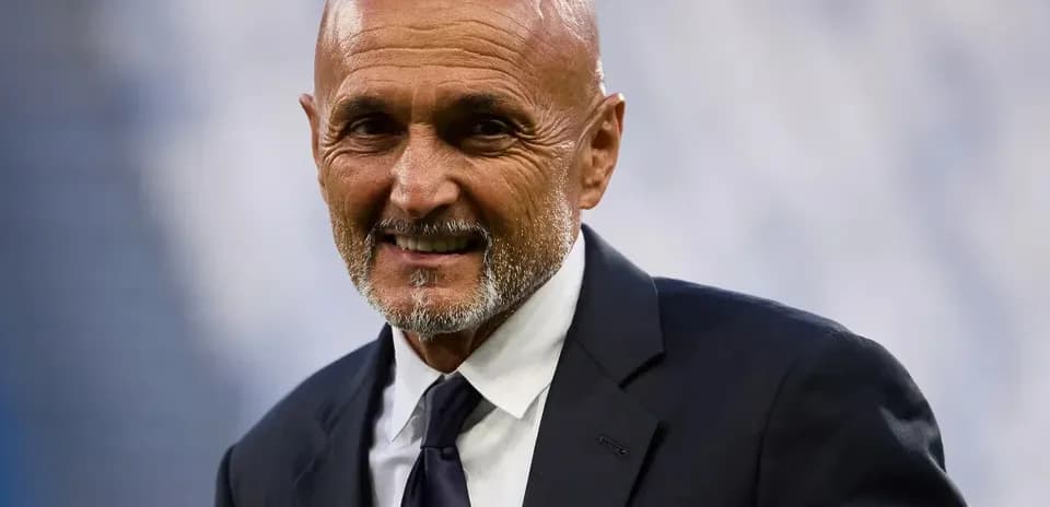 Coach smiling while wearing a suit at stadium