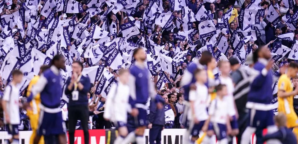Fans waving flags in Tottenham stadium during match