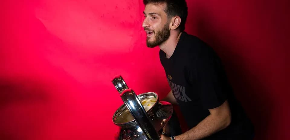 Player celebrating with a trophy against pink background