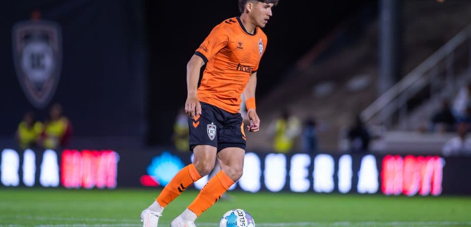 Player in orange kit dribbling the ball