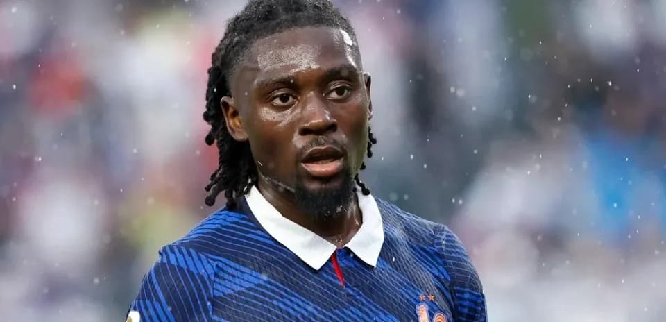 Football player in blue jersey during rainy match