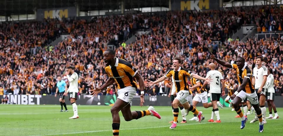 Player celebrating a goal with teammates and fans