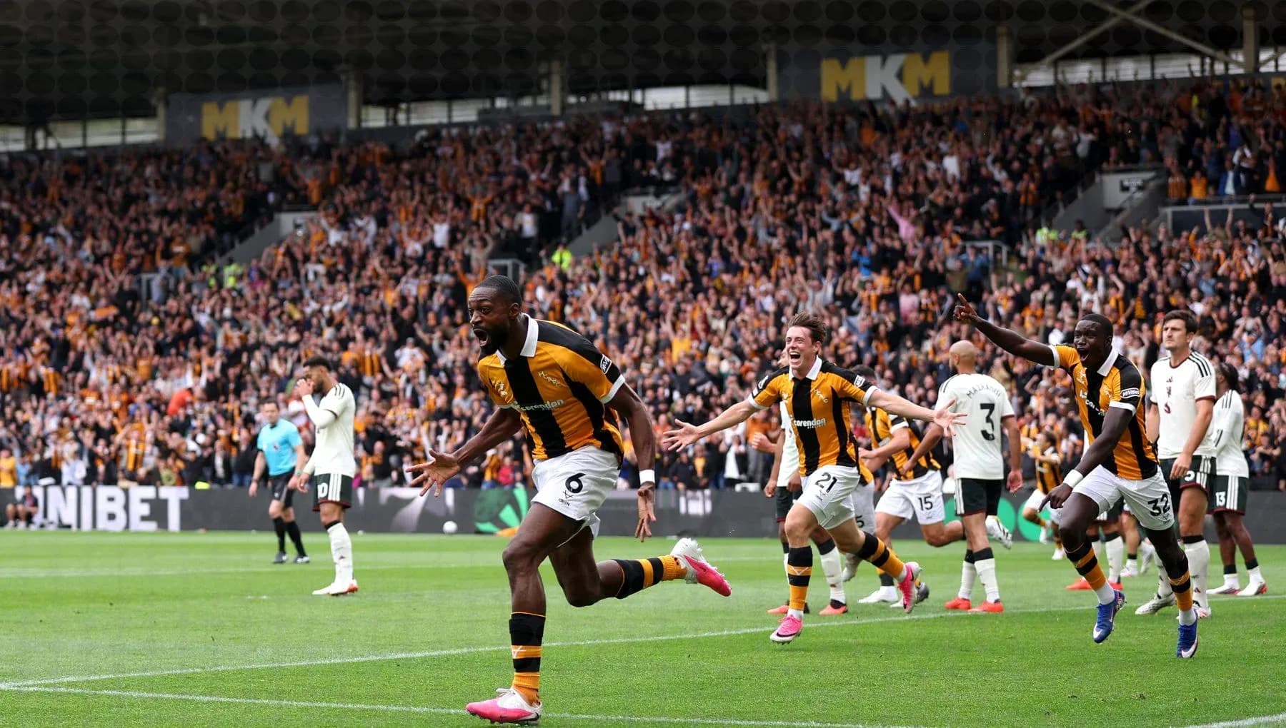 Player celebrating a goal with teammates and fans