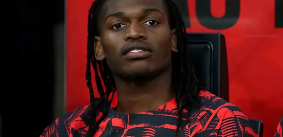 Player seated on bench in AC Milan jersey