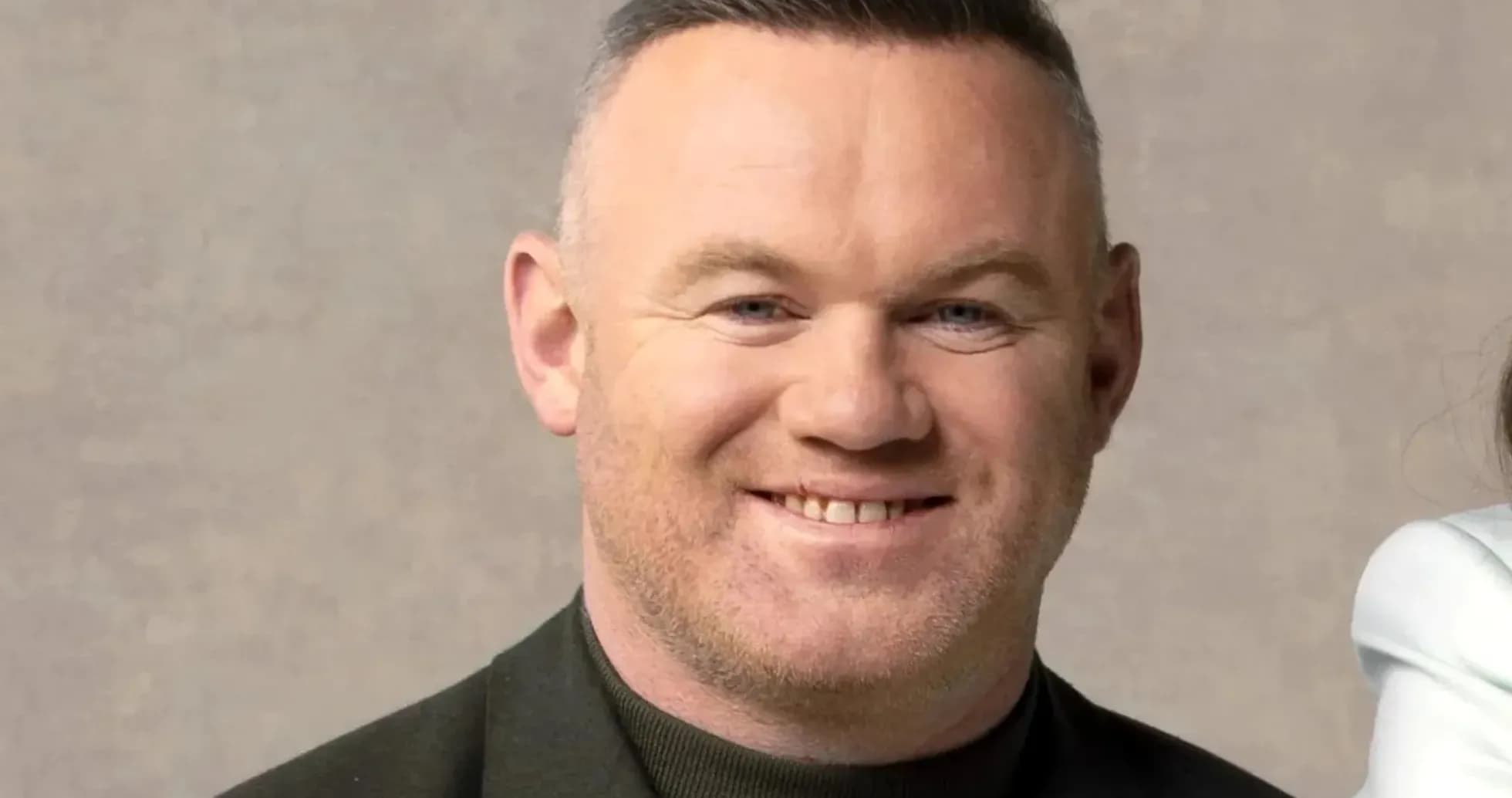 Man smiling in a dark jacket against neutral background
