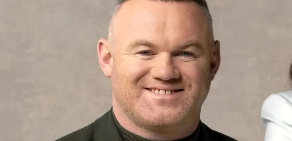 Man smiling in a dark jacket against neutral background