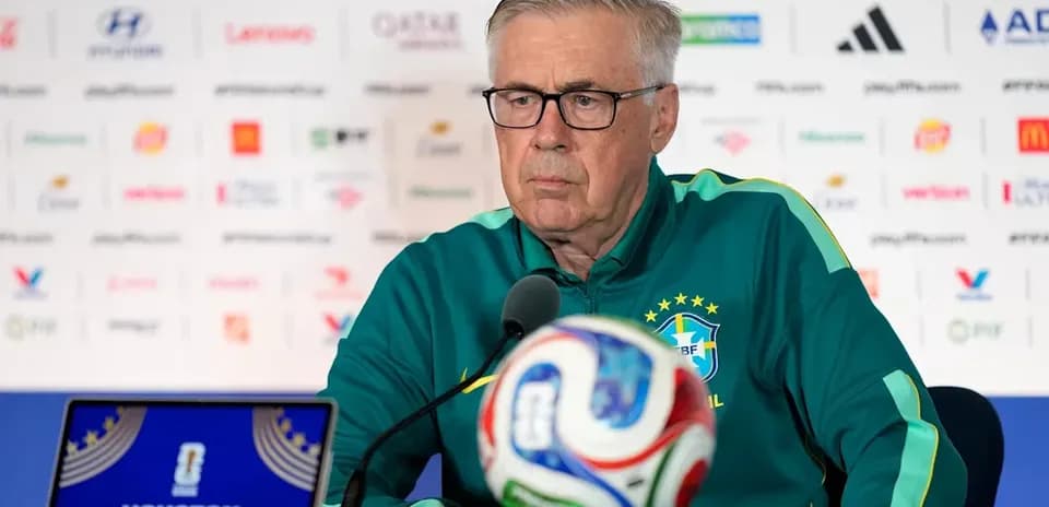 Coach at press conference with soccer ball and laptop