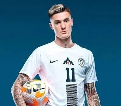 Player posing in team kit holding soccer ball