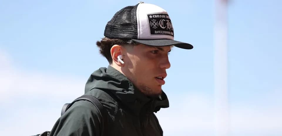 Player wearing a cap and earbuds arriving at venue