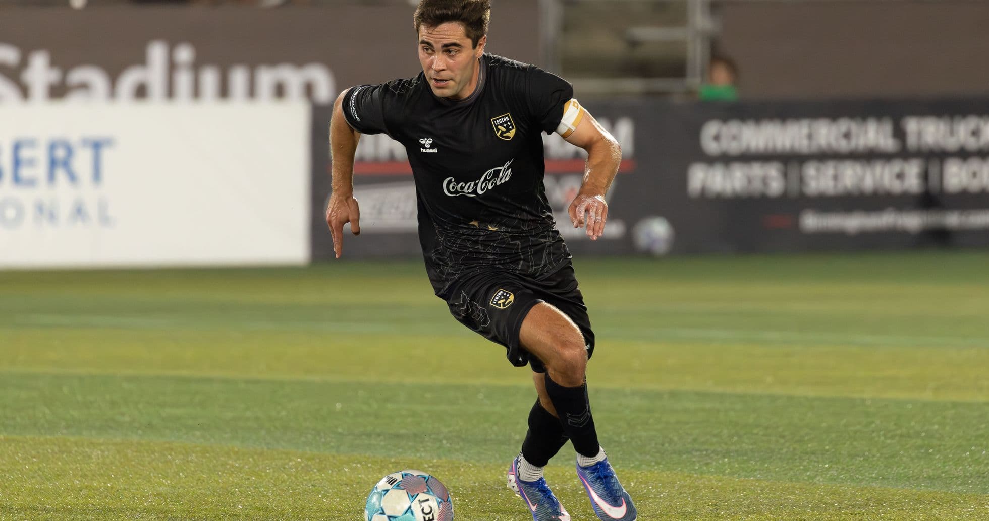Player in black jersey dribbling football