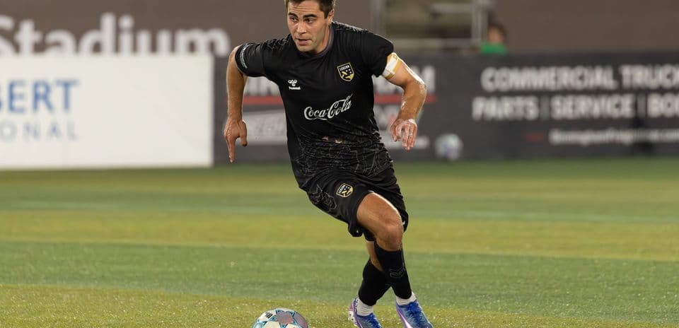 Player in black jersey dribbling football