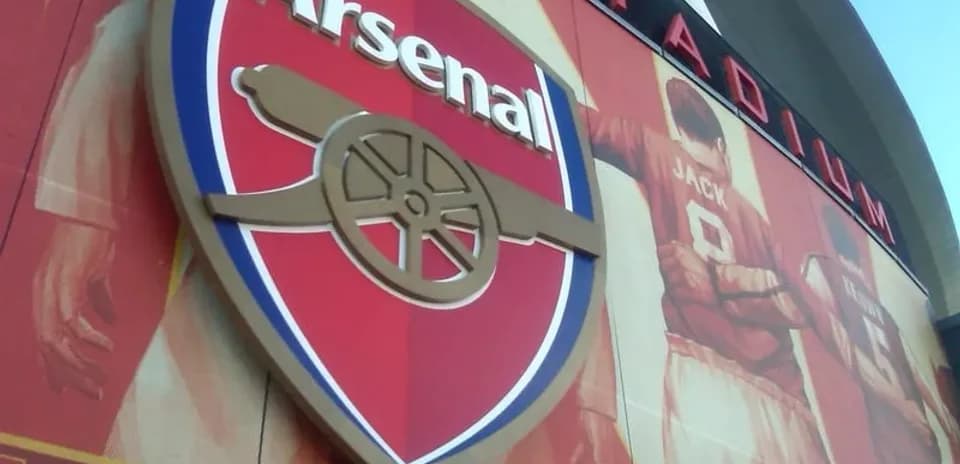 Arsenal logo on stadium wall with player mural
