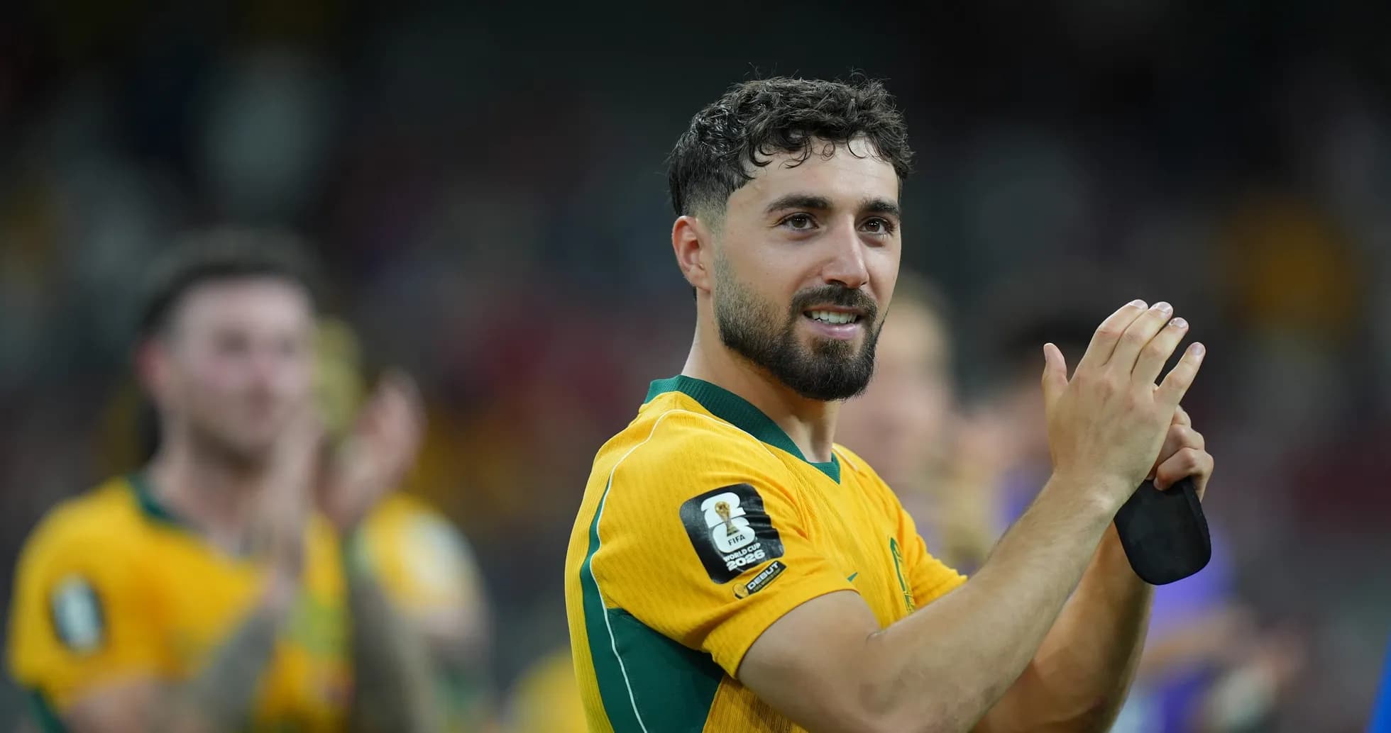 Player in yellow jersey applauding fans after match