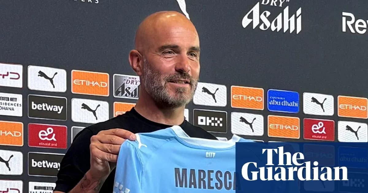 Manager holding Manchester City jersey at press conference