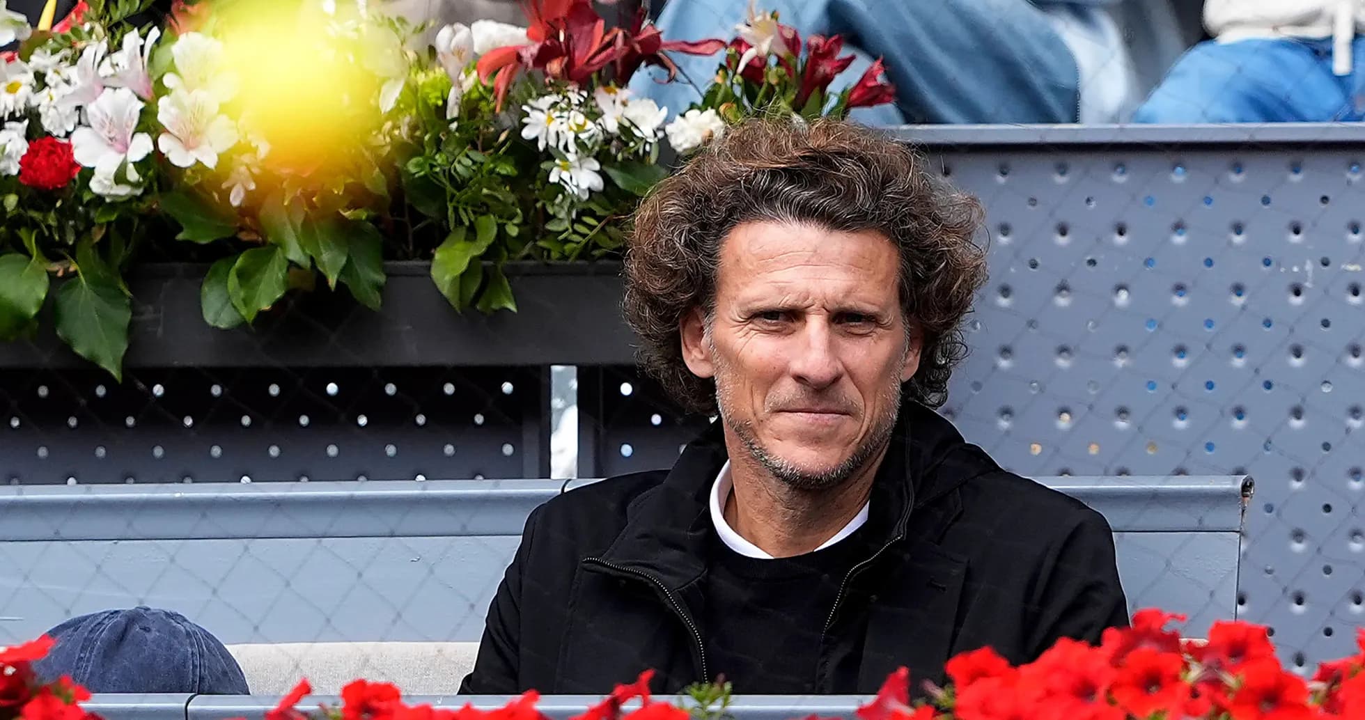Person sitting among flowers at tennis event