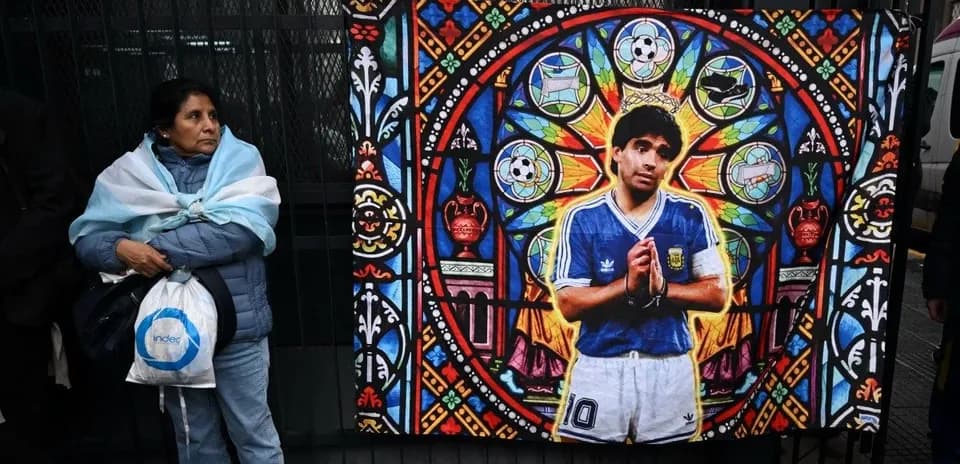 Woman standing beside Diego Maradona mural