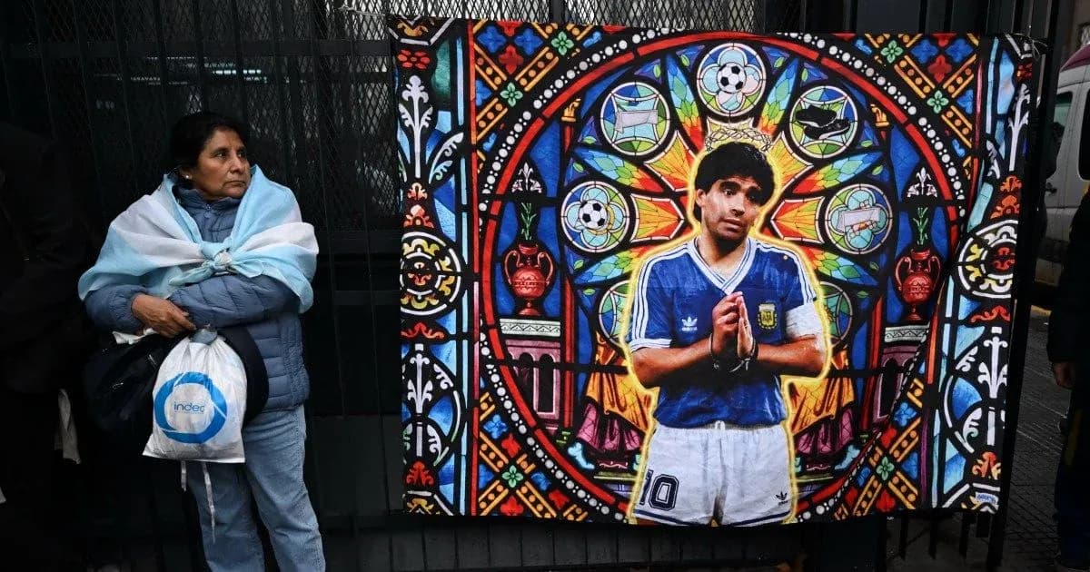 Woman standing beside Diego Maradona mural