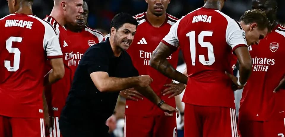 Manager instructing Arsenal players during a team huddle