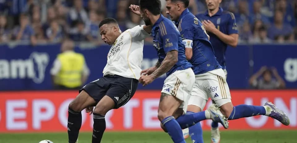 Real Madrid player challenged by Oviedo defenders