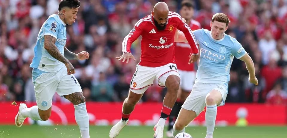 Manchester United player dribbling past Manchester City defenders