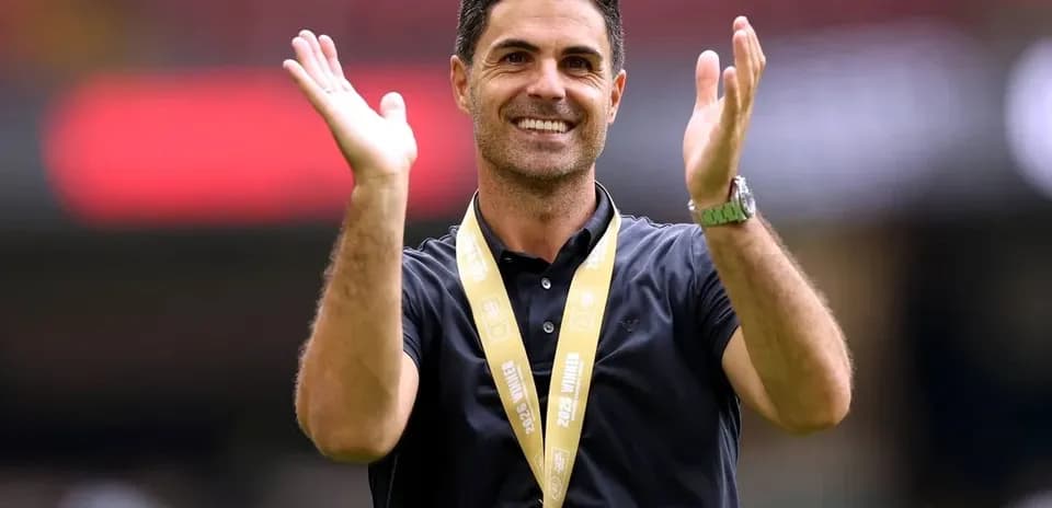 Coach celebrating with hands raised at stadium